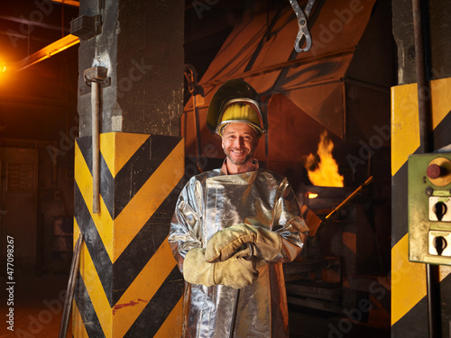 Smiling metal worker wearing protective workwear in steel mill photo