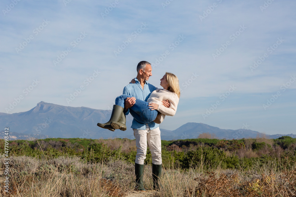 Romantic man carrying woman standing amidst plants Romantic man carrying woman standing amidst plants