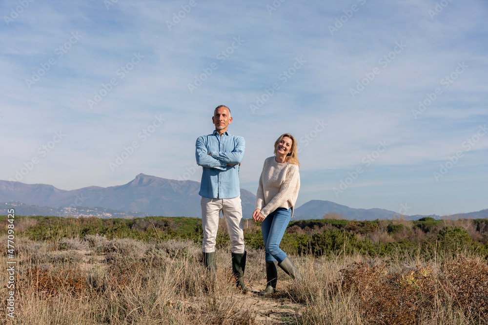 Smiling woman standing by man with arms crossed at dunes Smiling woman standing by man with arms crossed at dunes