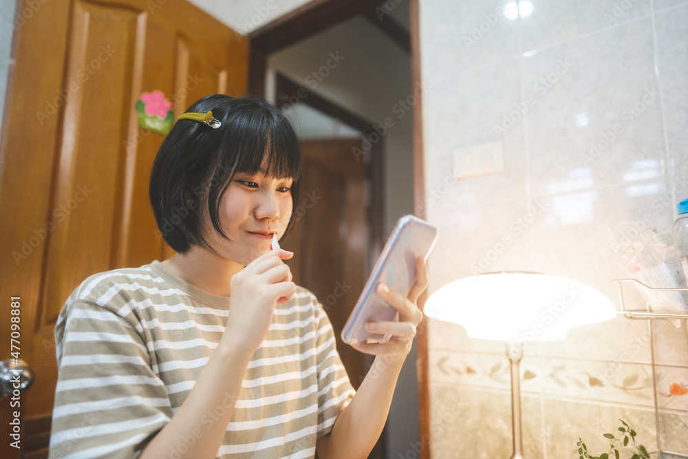 Young adult asian woman brushing teeth using mobile phone for online trading crypto in morning. Young adult asian woman brushing teeth using mobile phone for online trading crypto in morning.