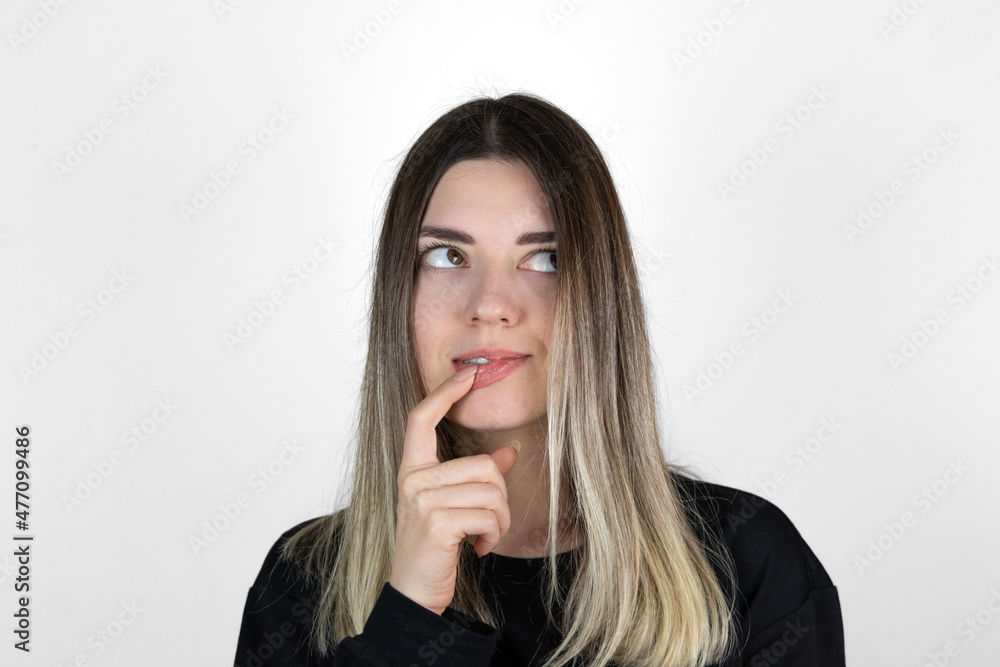 Young beautiful girl wearing casual clothes over isolated white background with hand on mouth thinking about question, pensive expression. Doubt concept. Smiling with thoughtful face. Young beautiful girl wearing casual clothes over isolated white background with hand on mouth thinking about question, pensive expression. Doubt concept. Smiling with thoughtful face.