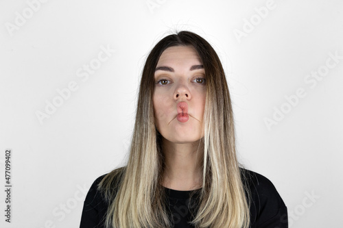 Close up indoor portrait of cool pretty young brunette girl. woman fooling around, making crazy funny grimace. Expressive facial expressions: White background. © burhan