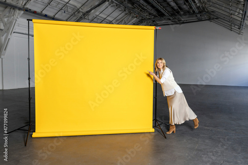 Businesswoman pointing at blank yellow backdrop