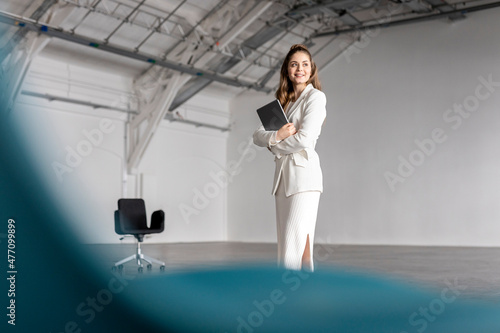 Thoughtful businesswoman standing with tablet PC at industial hall