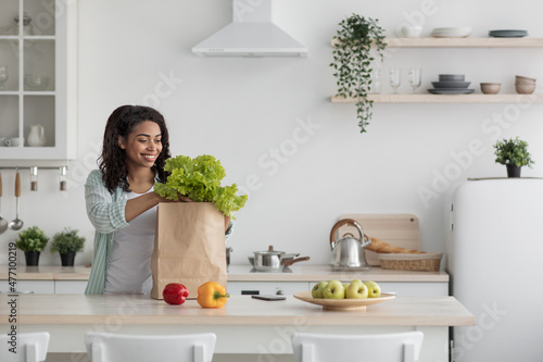Fresh organic vegetables, greens and fruits in eco brown paper bag on white table in kitchen