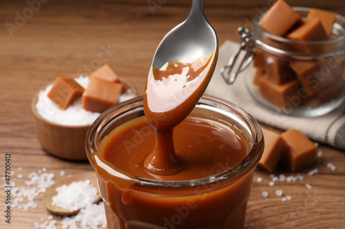 Taking tasty salted caramel with spoon from glass, closeup