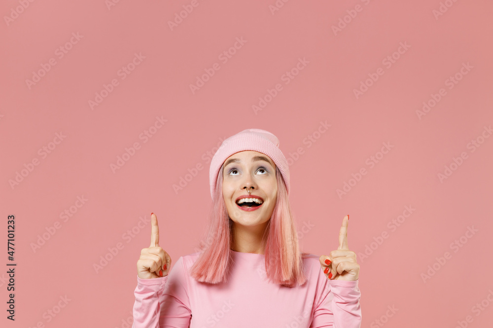 Young woman 20s with bright dyed rose hair in rosy top shirt hat point index finger overhead on workspace area mock up isolated on plain light pastel pink background. People lifestyle fashion concept Young woman 20s with bright dyed rose hair in rosy top shirt hat point index finger overhead on workspace area mock up isolated on plain light pastel pink background. People lifestyle fashion concept