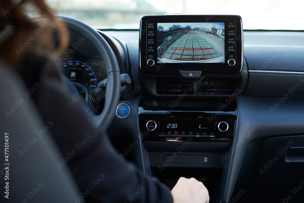 Businesswoman parking car through digital display of backup camera Businesswoman parking car through digital display of backup camera