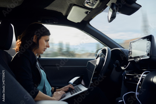 Businesswoman using laptop in driverless car photo
