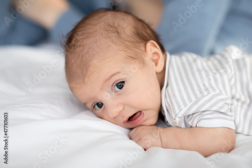 Closeup Portrait Of Cute Funny Newborn Baby Lying In Bed
