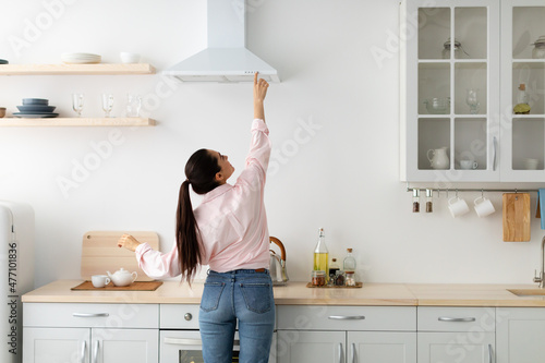 Φωτογραφία Back view woman select mode on cooking hood in kitchen