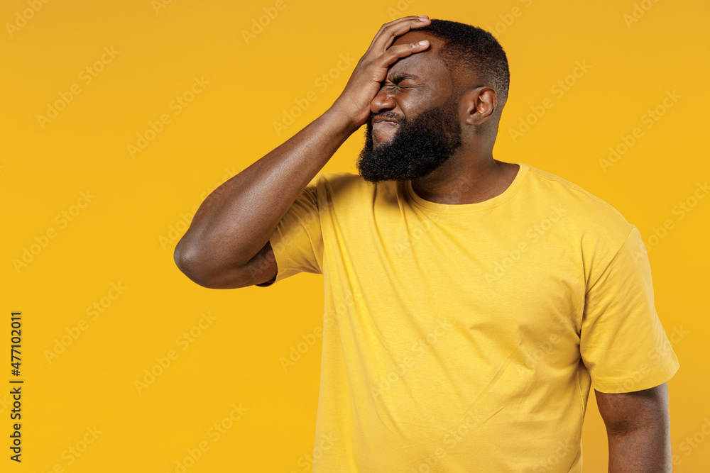 Young smiling happy black man 20s in bright casual t-shirt put hand on face facepalm epic fail mistaken omg gesture isolated on plain yellow color background studio portrait. People lifestyle concept. Young smiling happy black man 20s in bright casual t-shirt put hand on face facepalm epic fail mistaken omg gesture isolated on plain yellow color background studio portrait. People lifestyle concept.