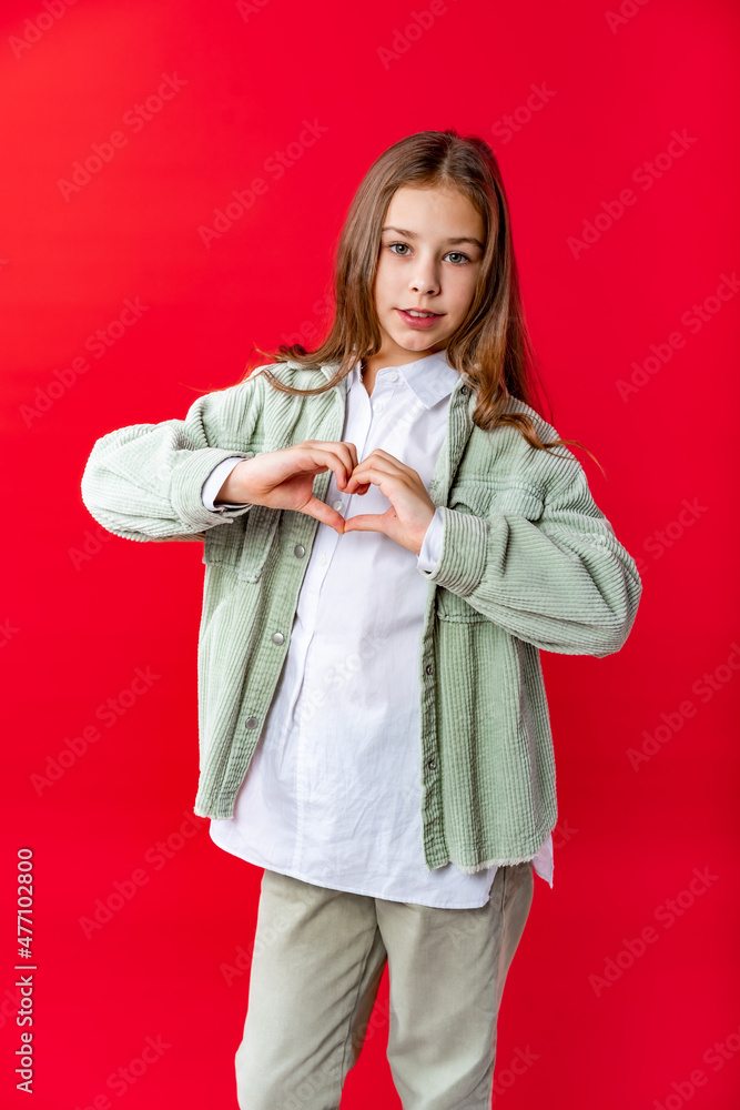 portrait of a beautiful girl in a green denim jacket and white shirt with loose hair. on a red background. portrait of a beautiful girl in a green denim jacket and white shirt with loose hair. on a red background.