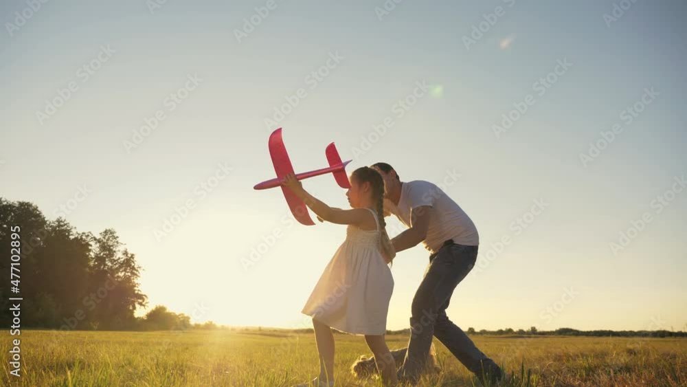 Happy family dad, daughter play plane in park at sunset. Father, family day dream in park. Freedom childish dream concept with airplane in hand. Dad, daughter dreaming play with toy airplane in nature Happy family dad, daughter play plane in park at sunset. Father, family day dream in park. Freedom childish dream concept with airplane in hand. Dad, daughter dreaming play with toy airplane in nature