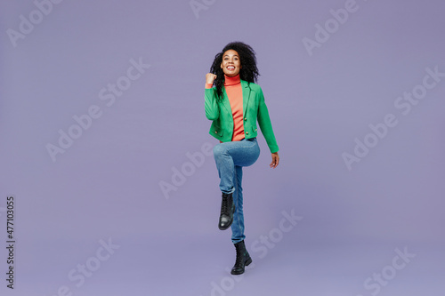 Full size body length excited young black curly woman 20s wears casual clothes doing winner gesture celebrate clenching fists say yes isolated on plain pastel light violet background studio portrait.