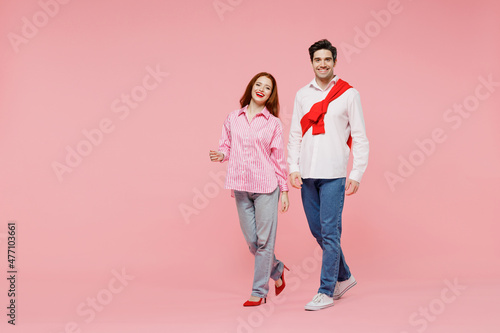 Full size smiling happy young couple two friends woman man in shirt look aside walking going isolated on plain pastel pink background studio portrait. Valentine's Day birthday holiday party concept.