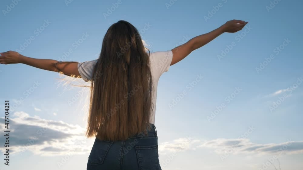 young woman against sky background.Girl stands with raised hands in sunny sky outdoors.girl enjoys freedom, happiness, raising her hands up.woman of freedom happiness, enjoying nature while traveling. young woman against sky background.Girl stands with raised hands in sunny sky outdoors.girl enjoys freedom, happiness, raising her hands up.woman of freedom happiness, enjoying nature while traveling.