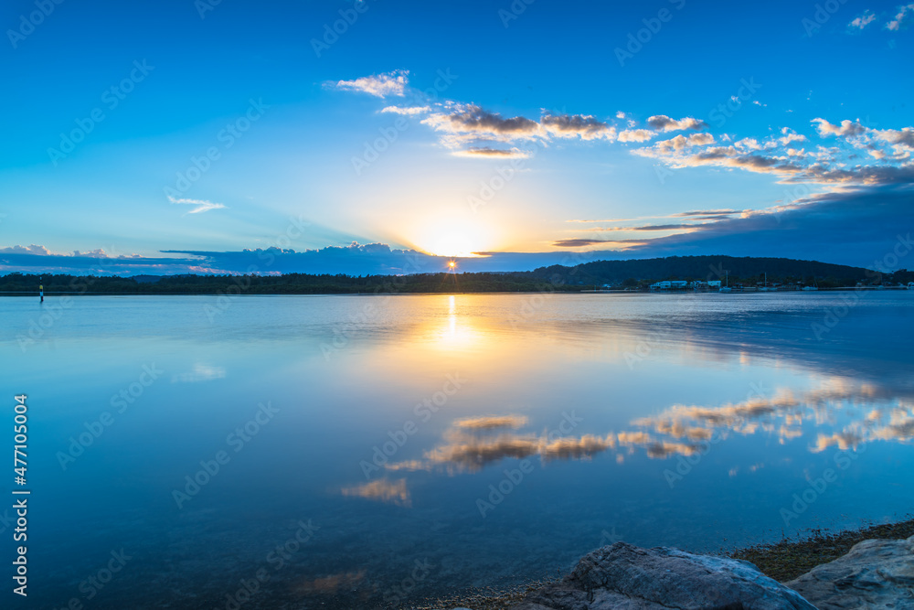 Sunrise waterscape with cloud reflections and sun rays