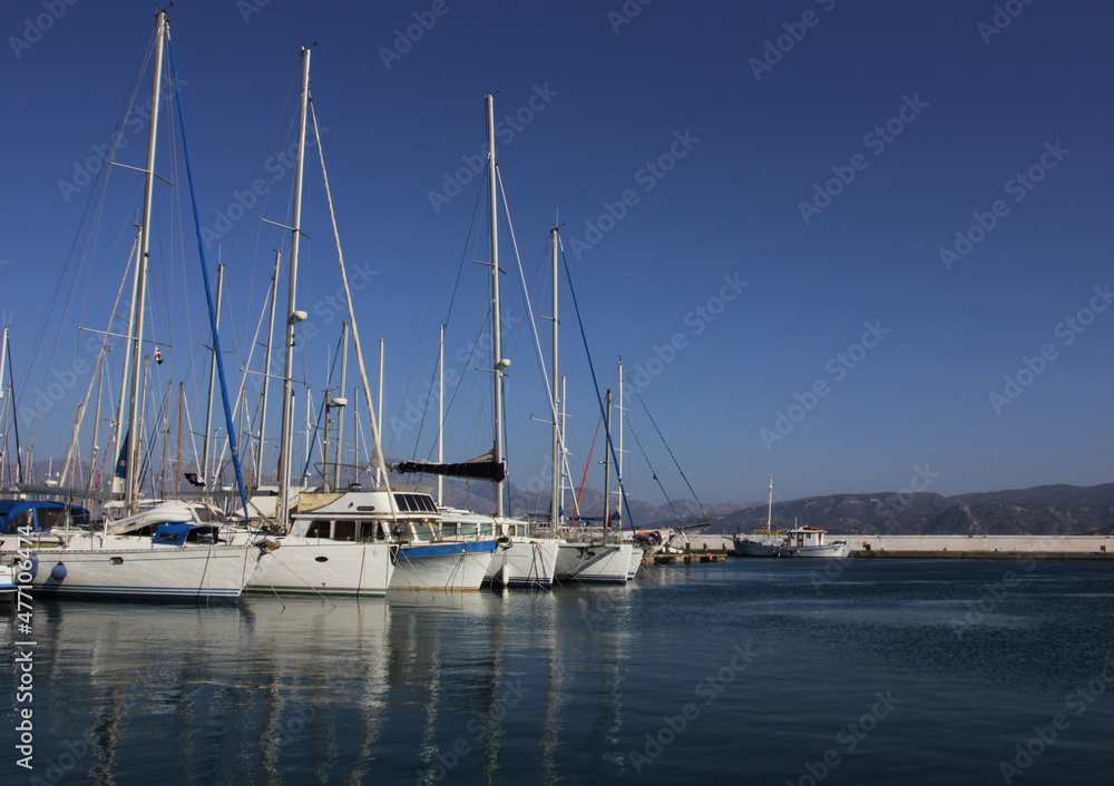 White yachts with high masts parked in a sea bay, marine or harbor.