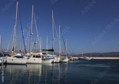 White yachts with high masts parked in a sea bay, marine or harbor.