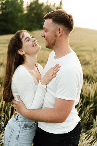 young couple in love stand in a wheat field at sunset of the day. guy with a girl on a romantic summer date. cute couple of lovers