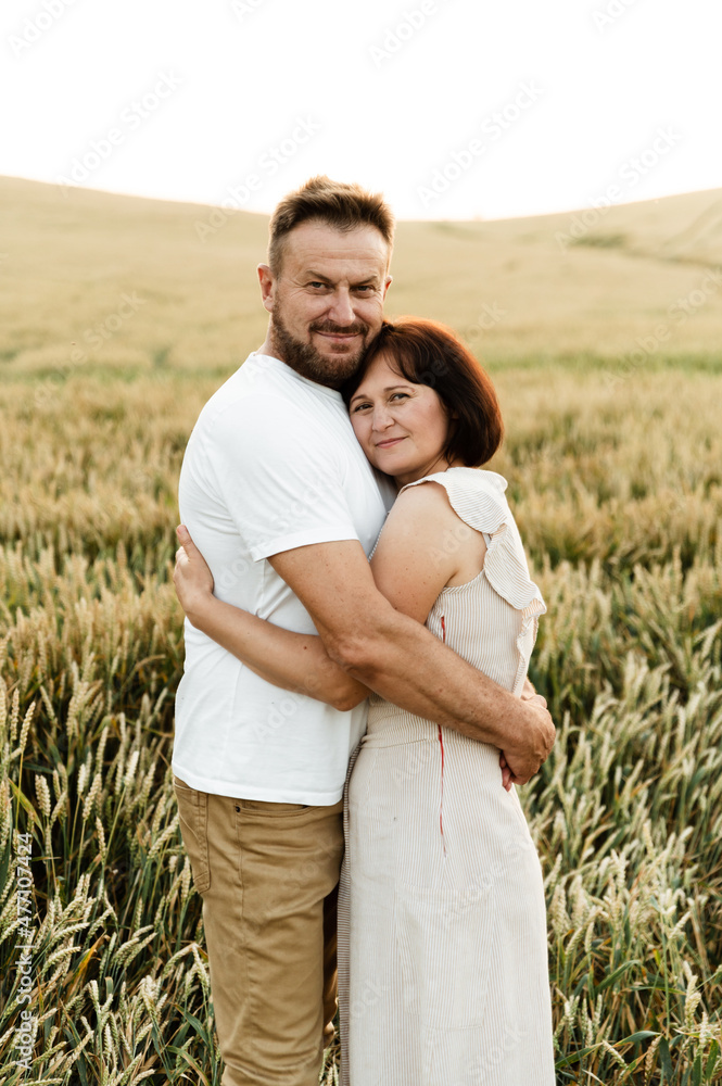 man and woman hugging while in the field. a walk of a middle-aged couple at sunset. a husband with a middle-aged wife. portrait of parents man and woman hugging while in the field. a walk of a middle-aged couple at sunset. a husband with a middle-aged wife. portrait of parents