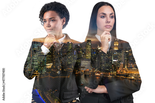 Two attractive businesswomen in suits, hand on chin. Asia corporate lifestyle, multinational diverse young professionals. Night Singapore city view. Double exposure photo