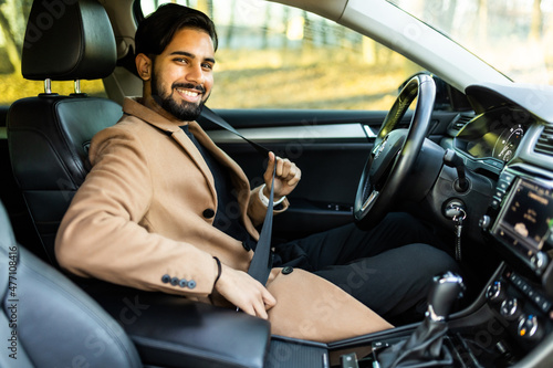 Portrait of smiling indian man fastening seat belt and sitting in his car. © F8  \ Suport Ukraine
