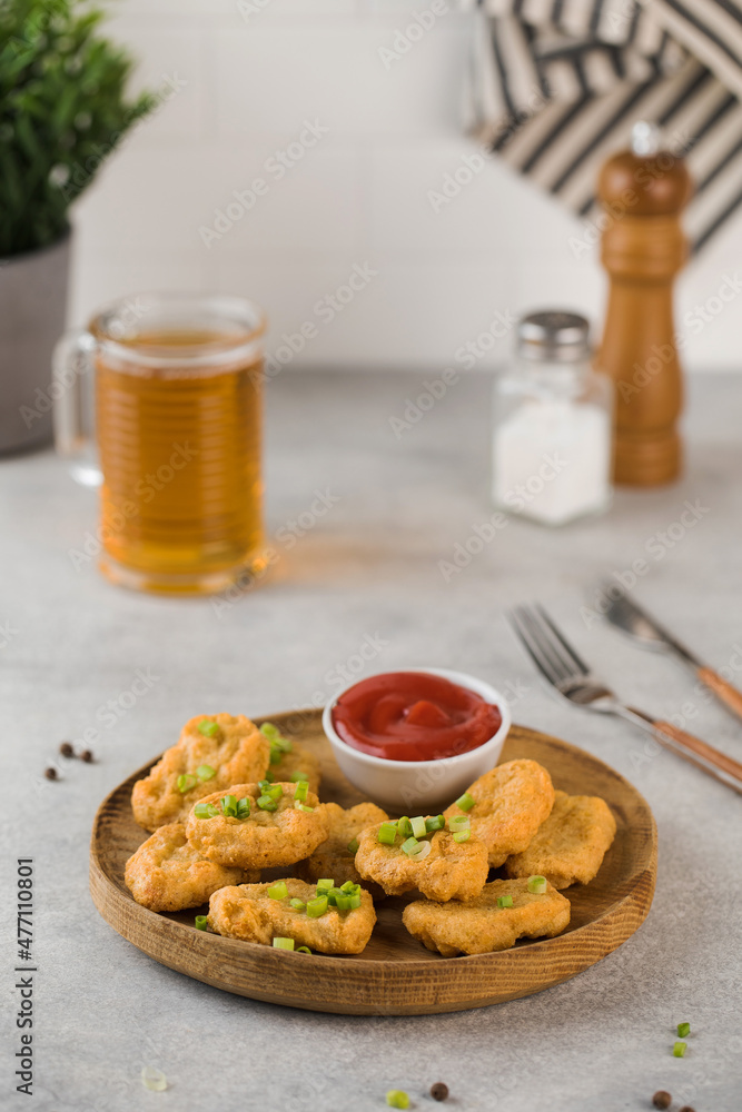 Golden chicken nuggets in a wooden plate, sprinkled with green onions and a lemon wedge. Pub menu
