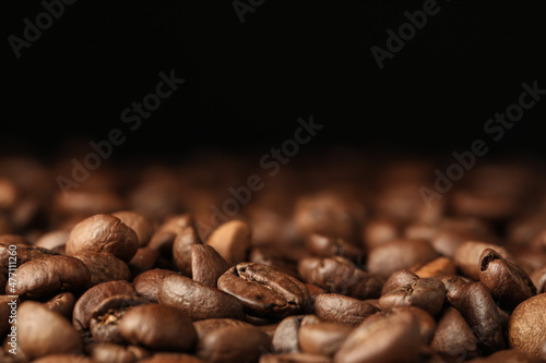 Many roasted coffee beans on black background, closeup. Space for text