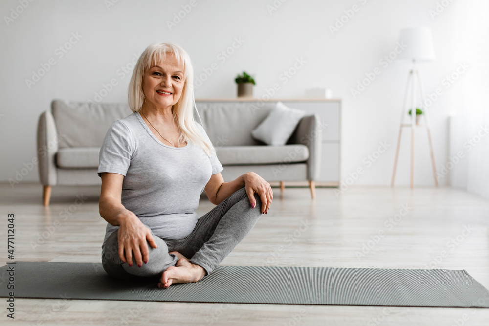 Mature woman exercising at home on yoga mat Mature woman exercising at home on yoga mat