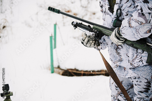 The sniper prepares the weapon for shooting in the winter from a prone position