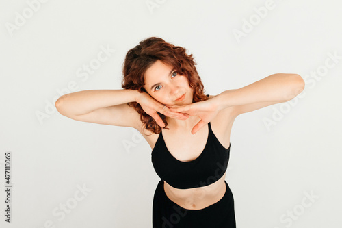 Happy cute redhead woman posing on white background, leaning on her hands and smiling, looking at the camera
