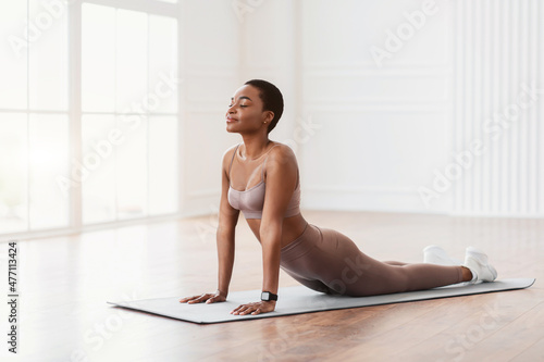 Young african woman stretching back on mat, cobra pose