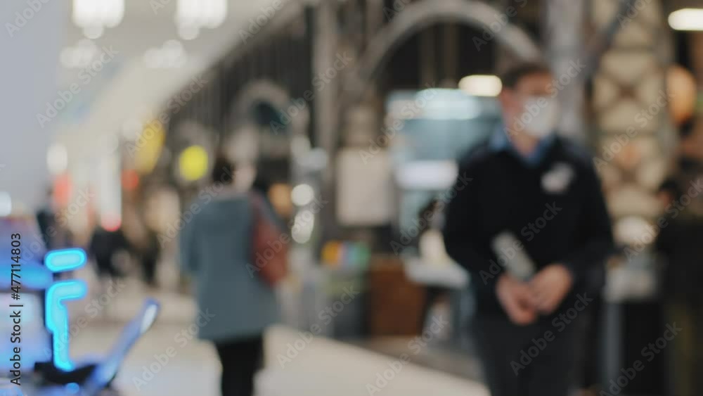 Blurred view background people walking moving public space supermarket shopping mall shoppers consumers, man in medical mask security. Sale concept. Buyers in market buying clothes foods in store. Blurred view background people walking moving public space supermarket shopping mall shoppers consumers, man in medical mask security. Sale concept. Buyers in market buying clothes foods in store.