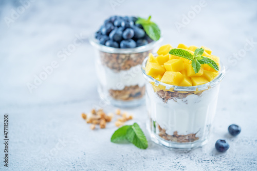 Mango and blueberry Greek yogurt granola parfait in a glass