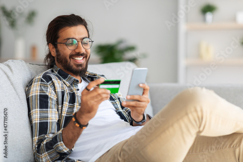 Cheerful indian man with credit card and mobile phone