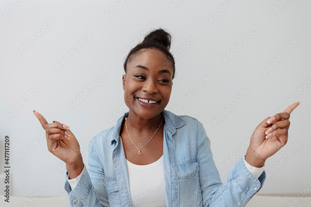 Cropped shot of a young black woman holding up her hands while standing against a grey background. Smiling young woman looking at camera and pointing away while standing against white background. Cropped shot of a young black woman holding up her hands while standing against a grey background. Smiling young woman looking at camera and pointing away while standing against white background.