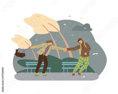 Male and female experiencing extreme wind weather at the park. Young people holding hands in severe storm and heavy rain