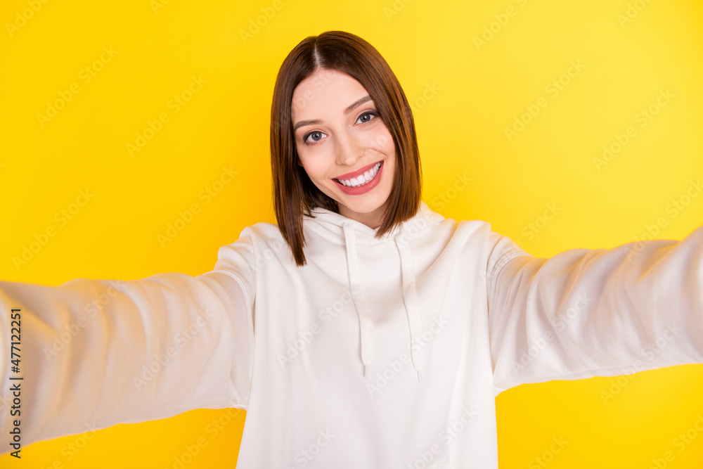 Photo of cheerful pretty cute lady shoot selfie shiny smile wear white hoodie isolated yellow color background Photo of cheerful pretty cute lady shoot selfie shiny smile wear white hoodie isolated yellow color background