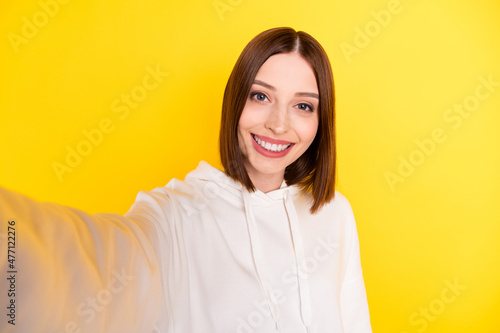 Self-portrait of attractive cheerful girl wearing cozy clothes good day isolated over bright yellow color background