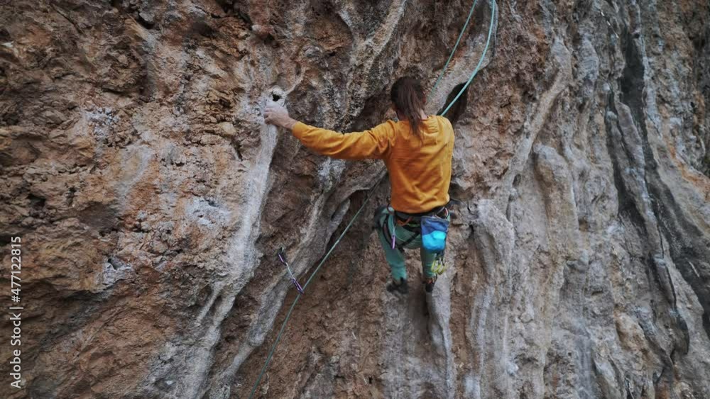 back view of strong skillful man rock climber climbs overhanging tough route with rock tufa, making very hard moves, trying to grip handhold on colonet and falling. climbing outdoors in Turkey back view of strong skillful man rock climber climbs overhanging tough route with rock tufa, making very hard moves, trying to grip handhold on colonet and falling. climbing outdoors in Turkey