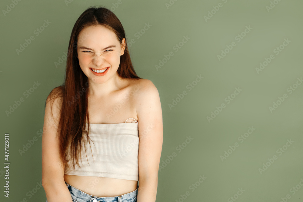 Portrait of young stylish positive woman laughing, looking at camera over green background Portrait of young stylish positive woman laughing, looking at camera over green background