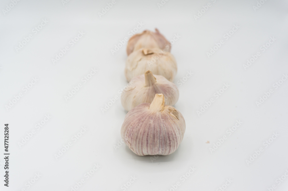 Ripe garlic in a straight line.Some garlic heads photographed against a white background. Still life shot. Purple and white garlic heads. Ripe garlic in a straight line.Some garlic heads photographed against a white background. Still life shot. Purple and white garlic heads.