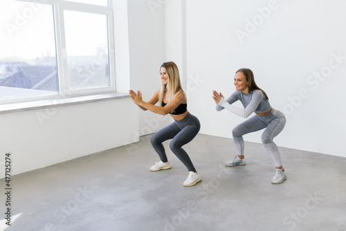 Two fit women doing squats at home, Female workout sport and fitness.