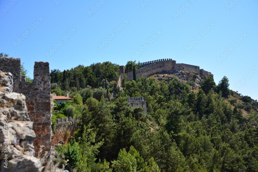 ancient fortress on top of mountain among green trees, Alanya
