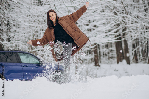 Woman in winter forest by her car