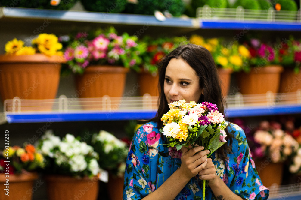 Smiling woman holding a bucket of flowers in a florist shop