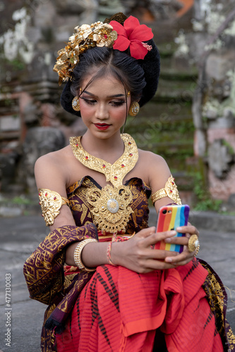 Young Balinese girl in traditional dress with a flower in hair, ocal temple in Bali, Indonesia. photo