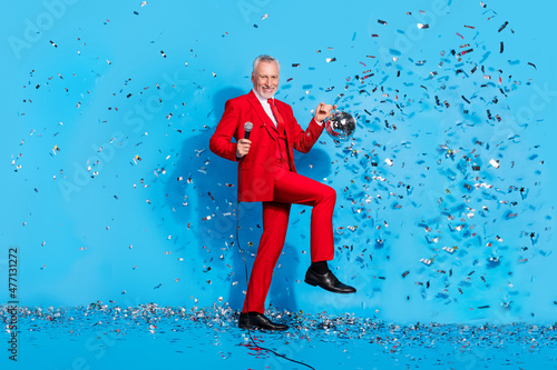 Photo of carefree dancer man hold mic shiny ball have disco fun wear red suit shoes isolated blue color background photo